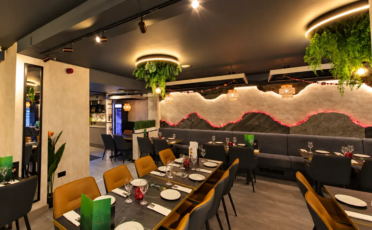 The Appayon dining room at night with warm pendant lights, laid tables and greenery