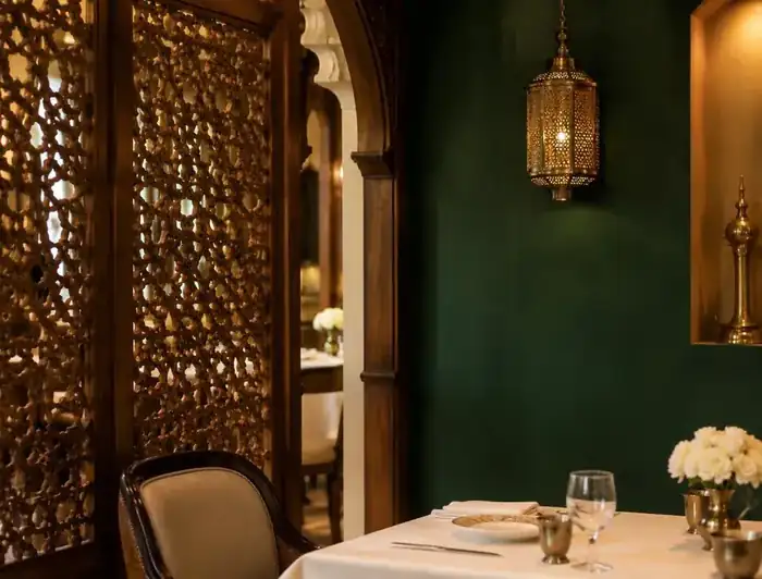 Carved wooden screen and brass lantern beside a cream-laid table in the restaurant